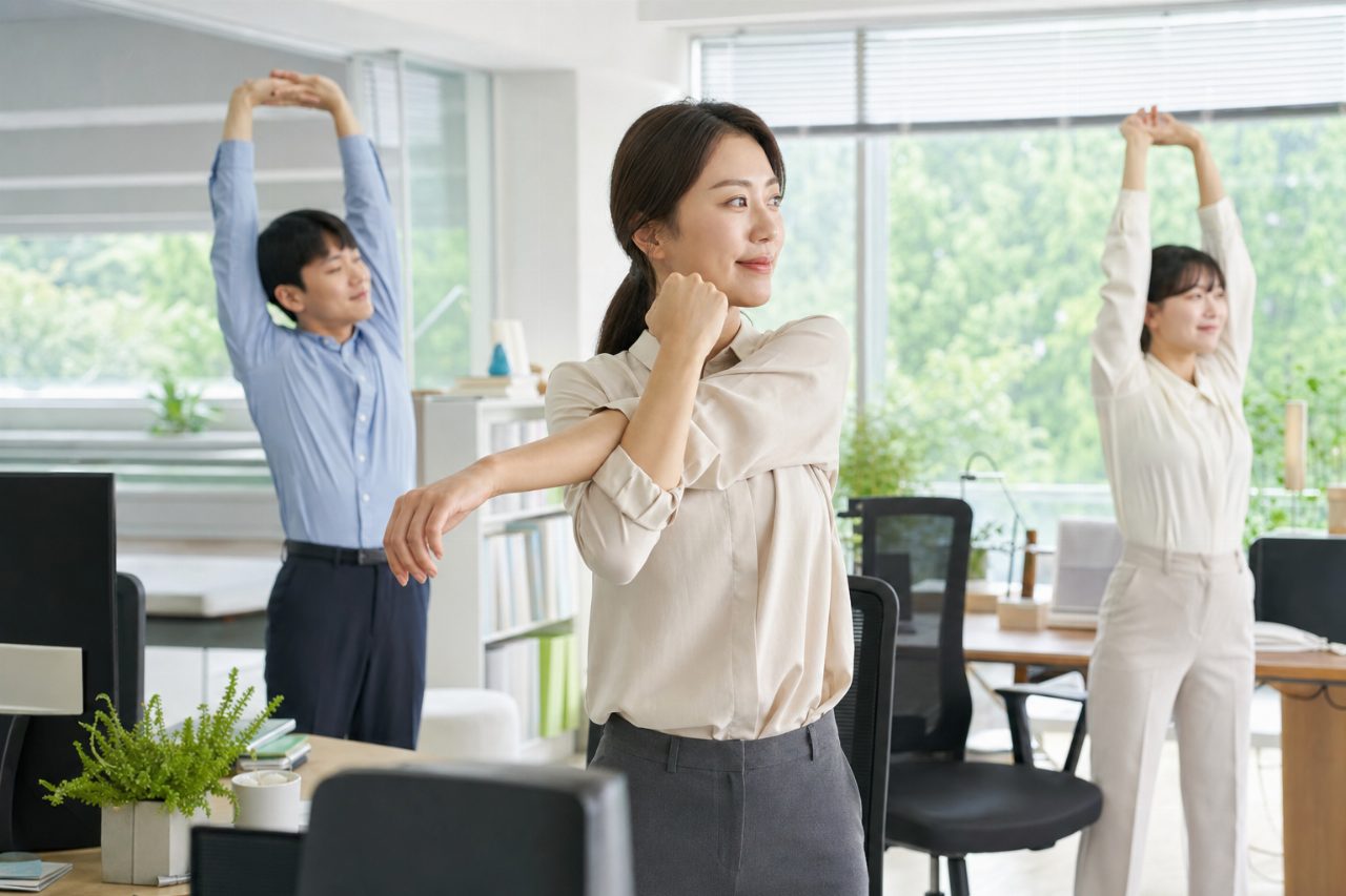 사무실에서 서서 스트레칭하는 모습이 연출된 밝은 공간.