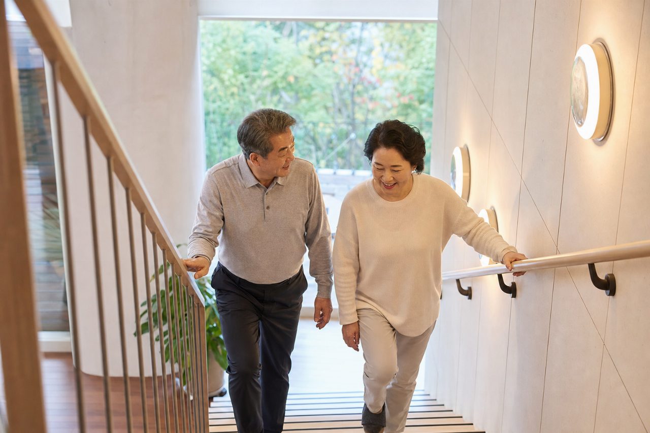 계단 옆에 견고한 손잡이와 밝은 조명이 설치된 실내 공간