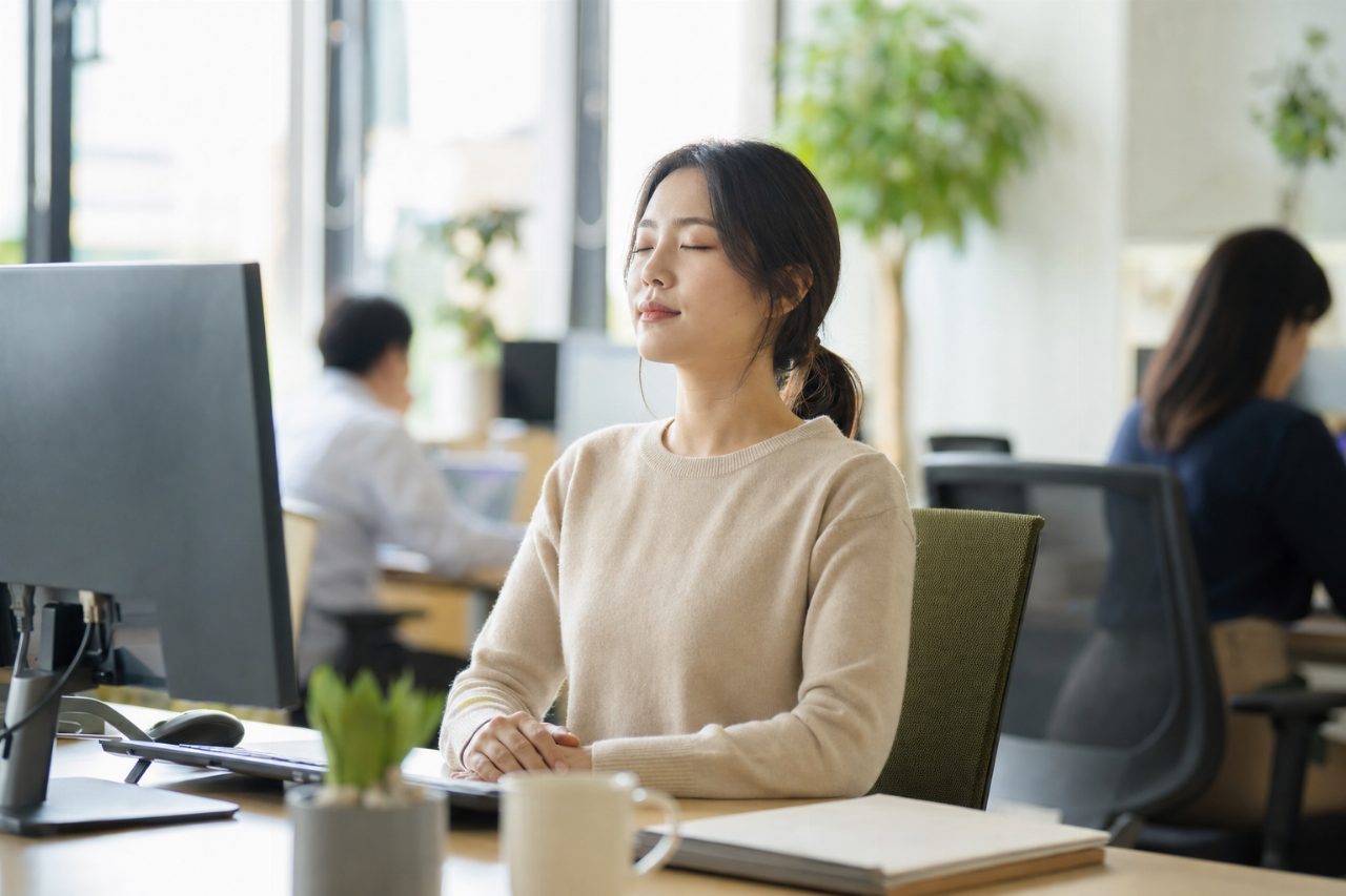 책상 앞에서 조용히 눈을 감고 숨을 고르는 장면